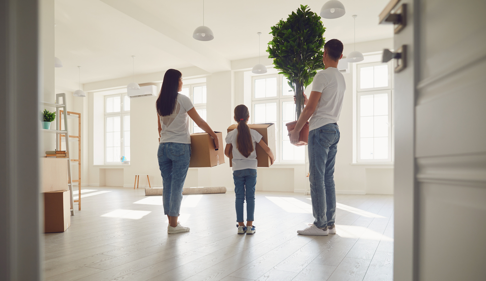 Happy family with children moving with boxes in a new house