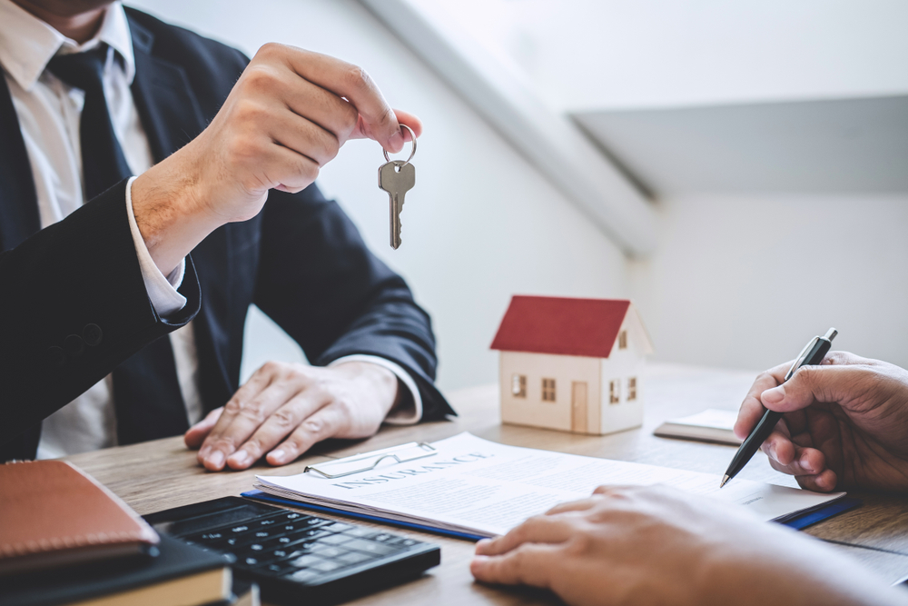 Estate agent giving house keys to client after signing agreement contract real estate